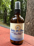 Calm the Storm Daily Intention Spray, 4 oz, on a wooden surface with trees in the background