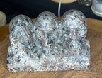 Speckled gray and black Yooperlite See No Evil, Hear No Evil, Speak No Evil Carving - 402 g by Sirius and the Wren, featuring three skulls depicting the classic motif.