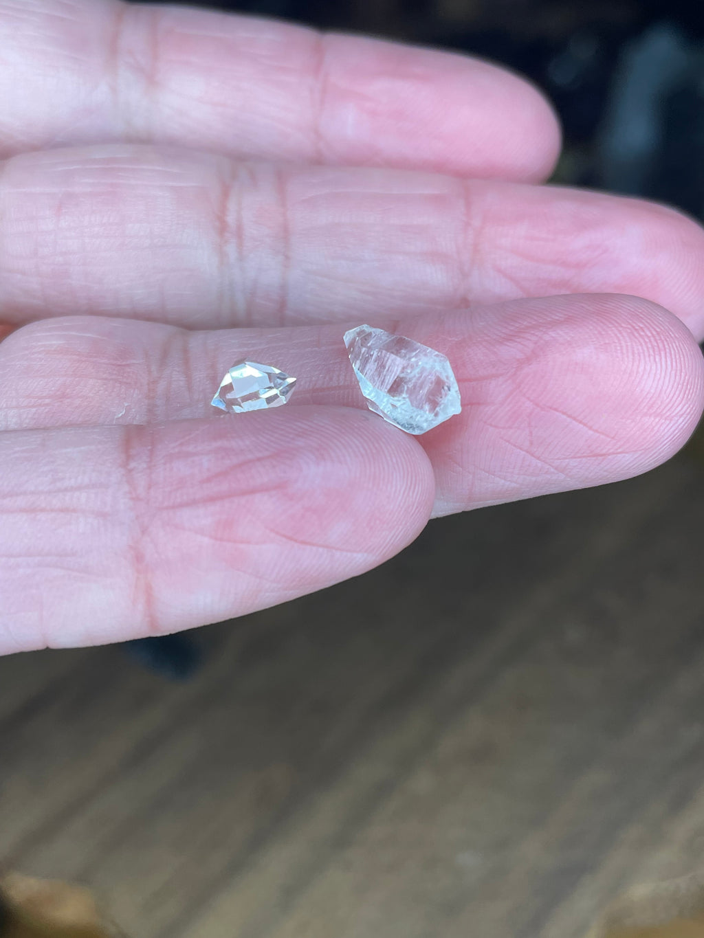 Two small, clear, faceted Moldavite with Herkimer Diamonds - 1.15 g crystals resting on the palm of a hand.