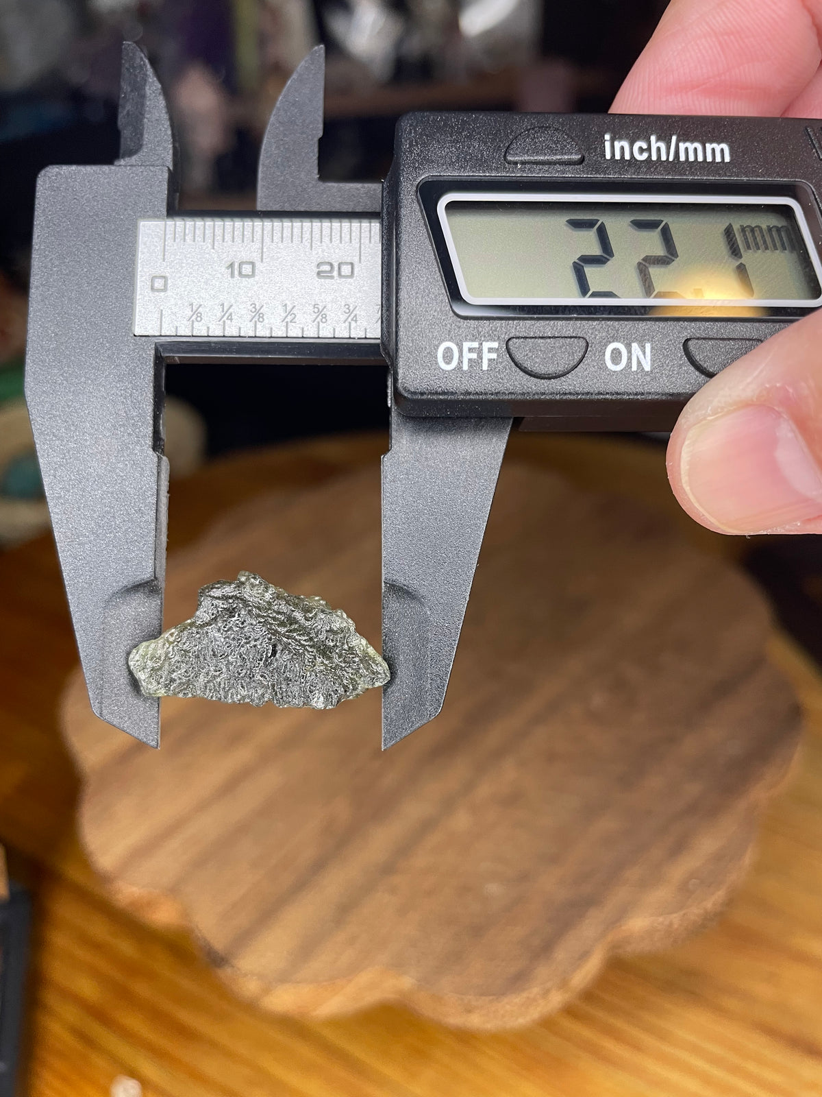 A rough green Moldavite with Herkimer Diamonds - 2.37 g fragment being measured by digital calipers reading 22.1 millimeters.