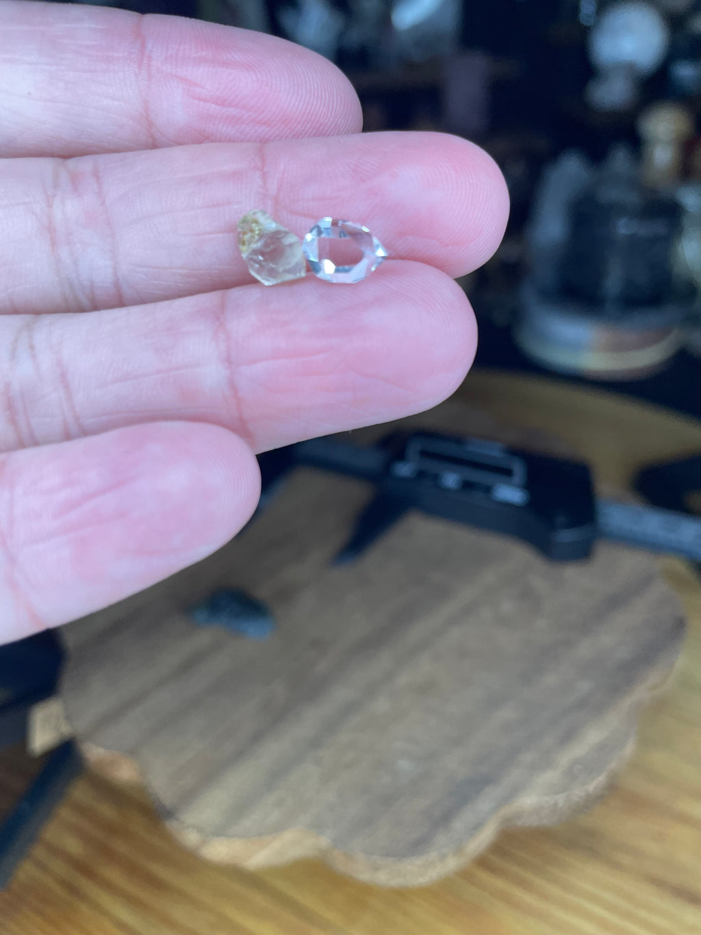 A hand holds a small green Moldavite with Herkimer Diamonds - 2.37 g, featuring a green moldavite stone and a clear, faceted Herkimer diamond between two fingers.