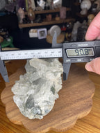 A digital caliper measures a Brazilian Blue Tara Quartz Cluster - 600 g, showing a reading of 90.8 millimeters across the translucent, light-colored crystals.