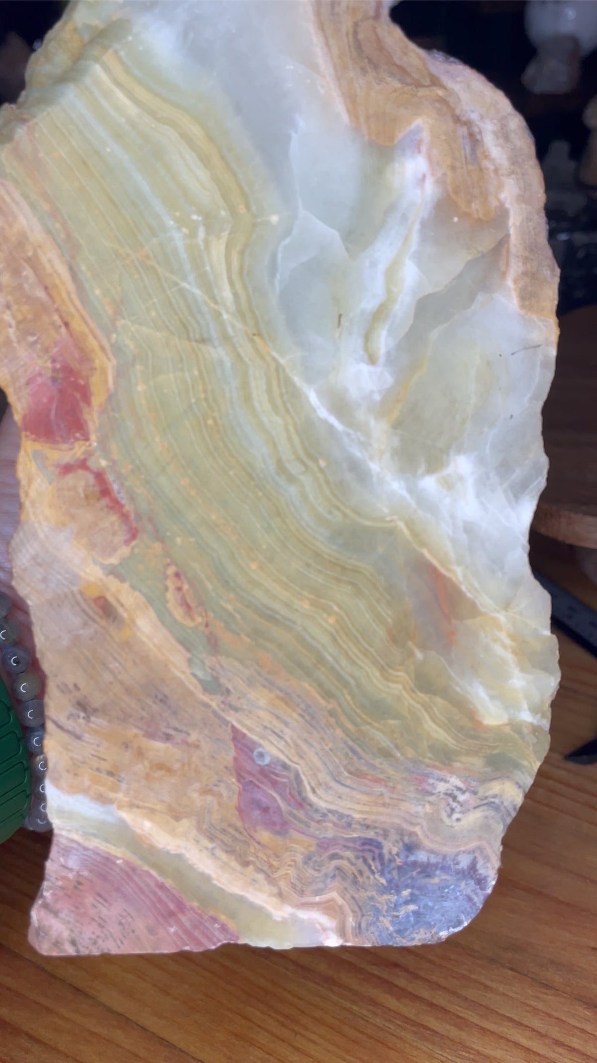 A large, translucent Large Green Banded Calcite (Green Onyx) Specimen featuring wavy layers of green, cream, and reddish-brown.