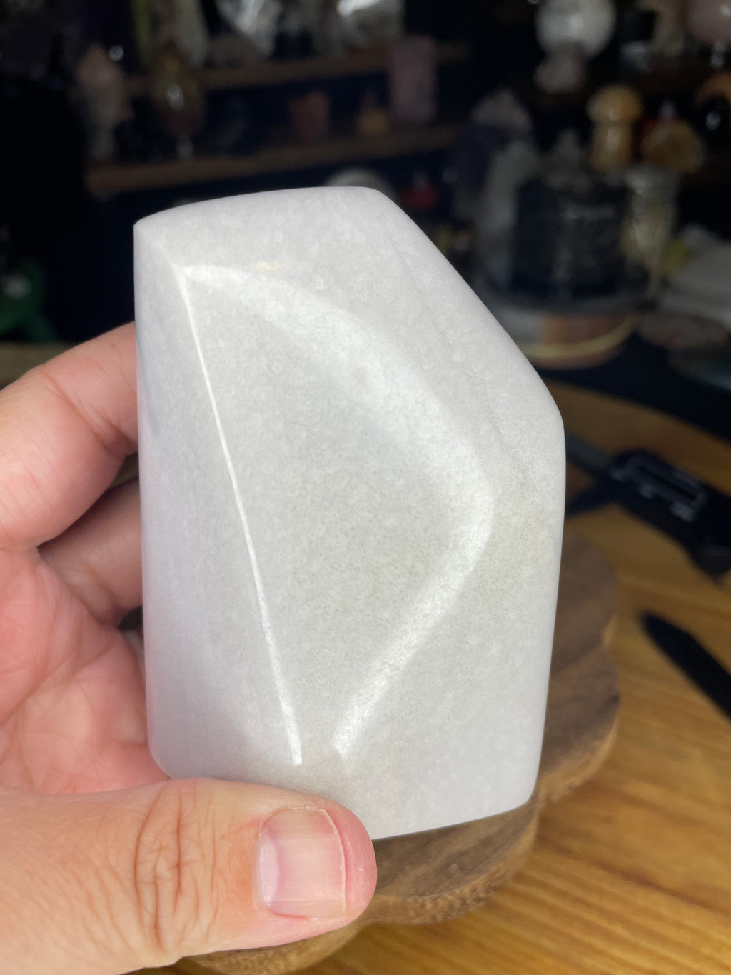 A hand holds a smooth, pale lavender Rare Lavender Yttrium Fluorite Freeform - 414 g.