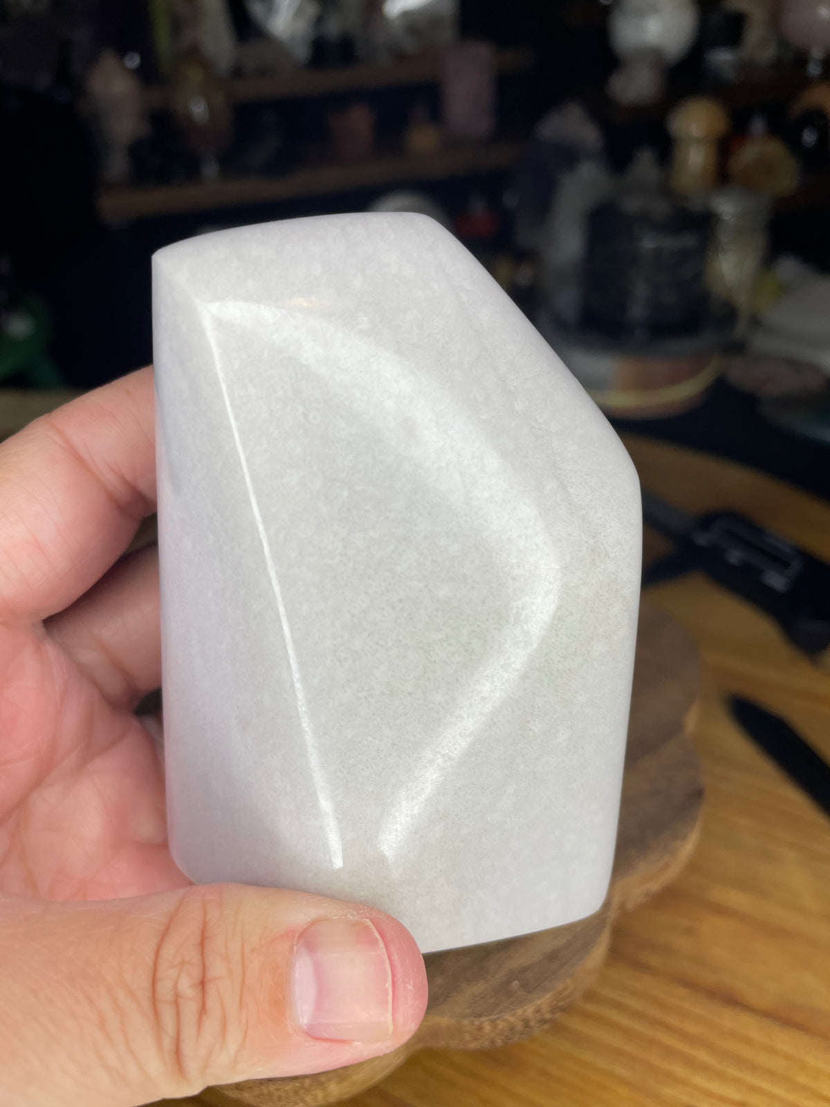 A hand holds a smooth, pale lavender Rare Lavender Yttrium Fluorite Freeform - 414 g.